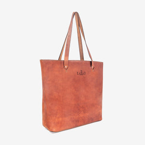 A large caramel brown handmade leather tote bag with hand stitching and etched logo detailing